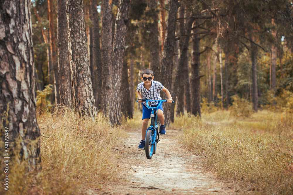 Happy kid cyclist rides in the forest on a bike. Happy kid cyclist rides in the forest on a bike.