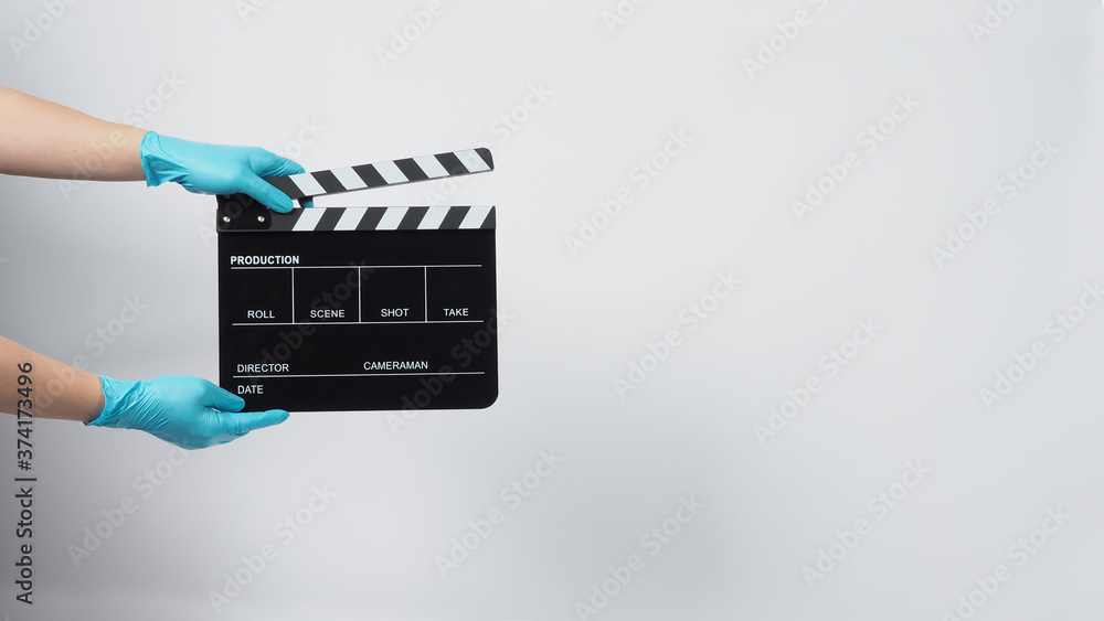 Hand is wear gloves and hold black Clapper board or movie slate. it use in video production and cinema industry on white background.