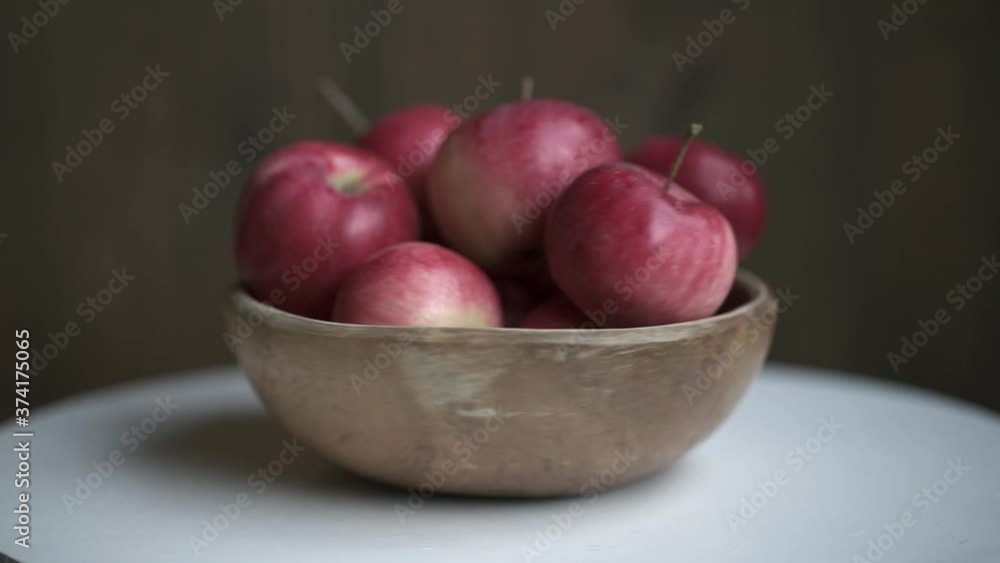 Red apples in wooden bowl rotate on white table. Loopable moving image. Red apples in wooden bowl rotate on white table. Loopable moving image.