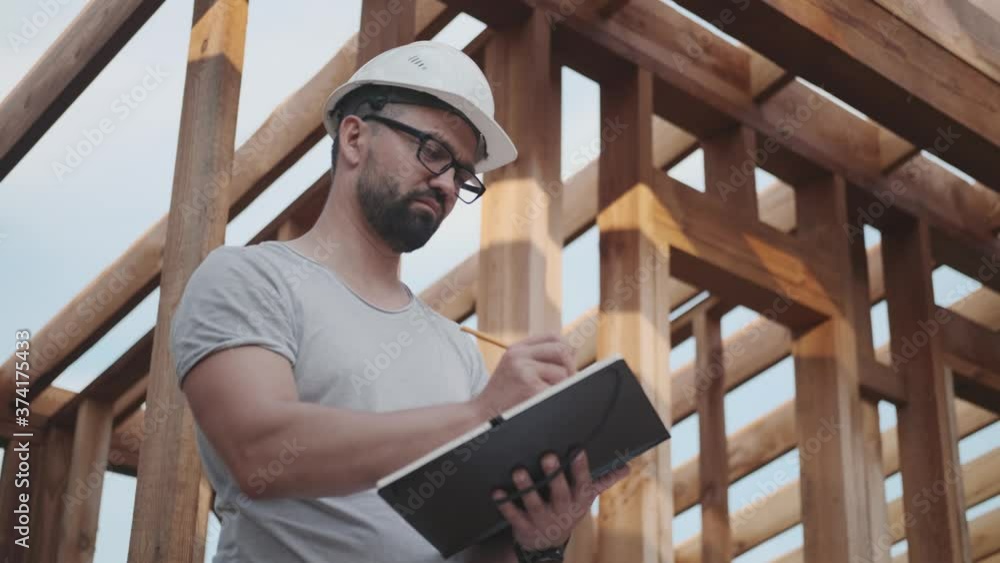 An engineer supervises the construction of a wooden house. An engineer supervises the construction of a wooden house.