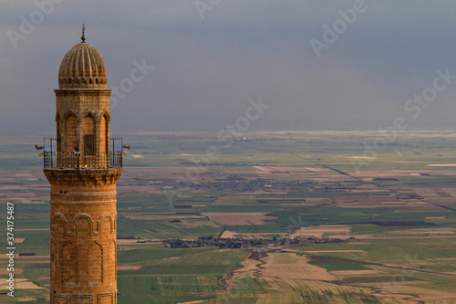 Minaret of the Great Mosque, known also as Ulu Mosque, with the Mesopotamia plain and Syrian border on the background, in Mardin, Turkey