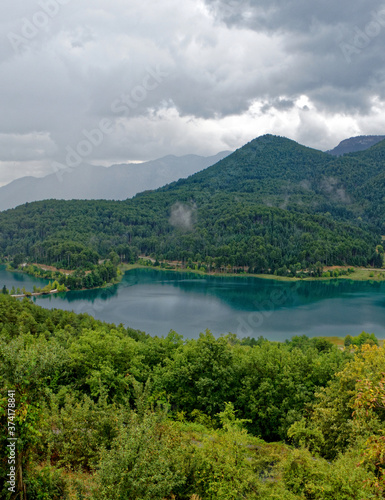 picturesque mountain lake and green forest under cloudy sky