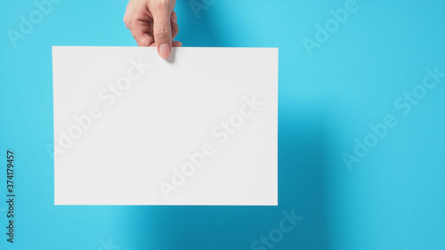 Hand is holding the A4 paper on blue background.