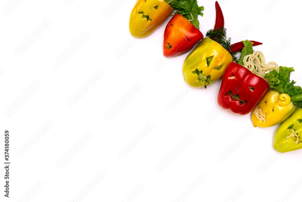 Multicolored stuffed peppers with various cutout faces in the skin on a white background. Concept preparation for Halloween. Multicolored stuffed peppers with various cutout faces in the skin on a white background. Concept preparation for Halloween.