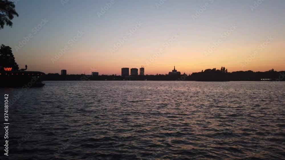 Waves on Herastrau Lake, Bucharest at sunset with distant buildings on background Waves on Herastrau Lake, Bucharest at sunset with distant buildings on background