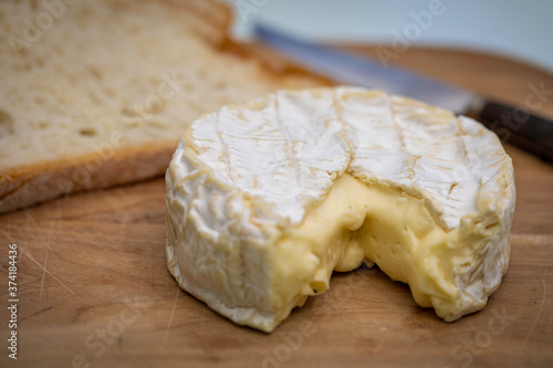 French Camembert cheese over a wooden table with some bread slices on the background