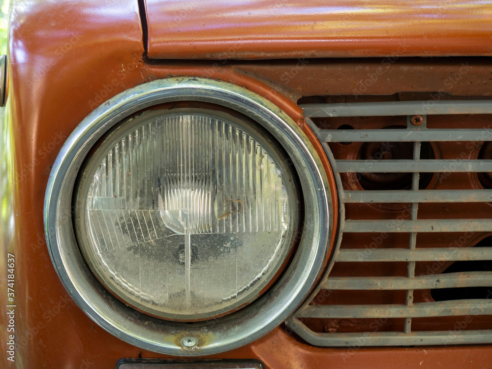Shiny orange vintage car. Detail view of the headlight. Retro Soviet car. Front light. Retro automobile scene. Circle headlamp.