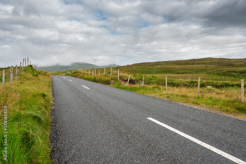 Small asphalt road in Connemara, county Galway, Ireland, Nobody, Dramatic cloudy sky.