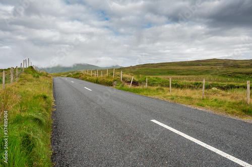 Small asphalt road in Connemara, county Galway, Ireland, Nobody, Dramatic cloudy sky.