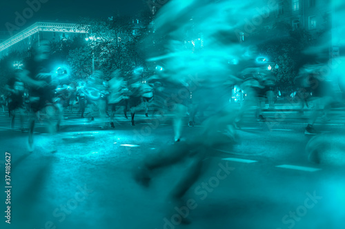 Silhouettes of a group of runners on the city road  illumination  abstract  motion blur  night festival. Concept of a modern lifestyle  healthy lifestyle  green background.