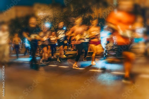 Large group of running athletes on street, night city marathon, blur effect, unrecognizable peole. Sport, fitness, lifestyle concept. Abstract background