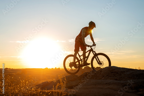 A cyclist rides a mountain bike on the rocks during sunset, a copy of the free space. © mihakonceptcorn