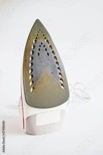 Dirty surface Iron for ironing things on a white isolated background. Concept breakdown or problem, laundry, sewing studio, housework. Damaged iron surface