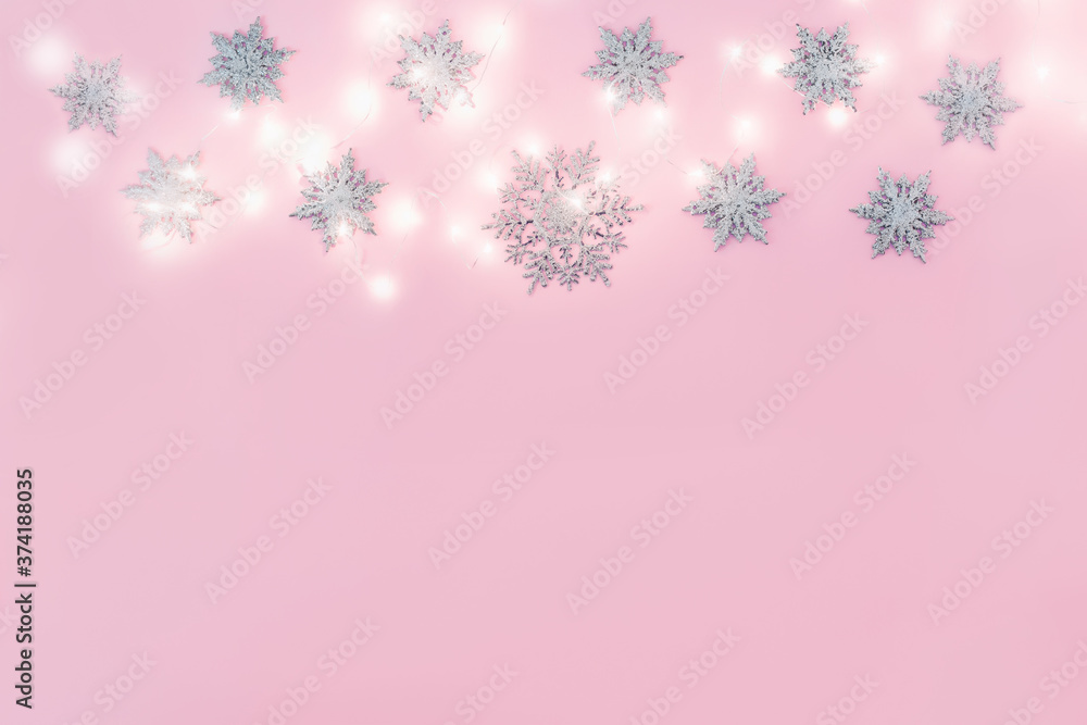 Christmas decor snowflakes with garland on pink background. Copy space. Christmas decor snowflakes with garland on pink background. Copy space.