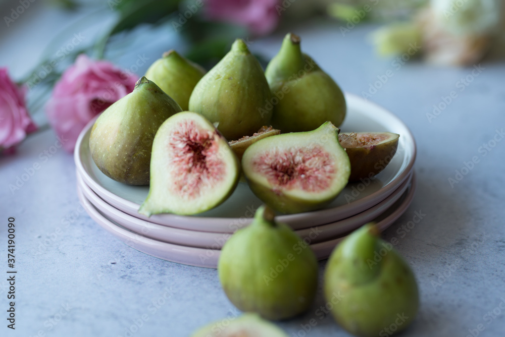 Ripe whole half and sliced figs among flavored green leaves of herbs and colorful flowers Ripe whole half and sliced figs among flavored green leaves of herbs and colorful flowers