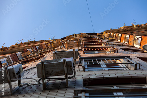 Multi-storey residential building. The front of the house is hung with air conditioning and satellite dishes. Bottom view