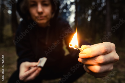 Tableau sur toile Woman rebel with burning match in hands in dark