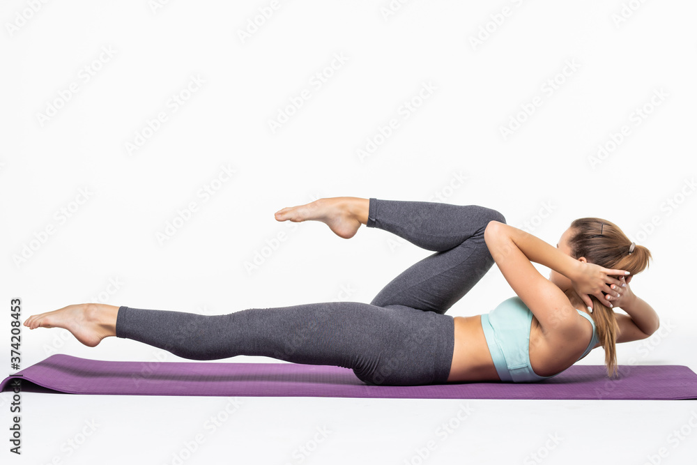 Young woman exercising and doing a crunch to work her abs isolated white background Young woman exercising and doing a crunch to work her abs isolated white background