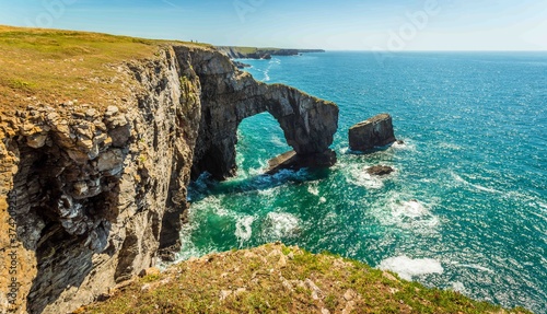 A panorama view of the impressive natural arch made from Carboniferous Limestone, know as the Green Bridge of Wales on the Pembrokeshire coast, near Castlemartin in early summer photo