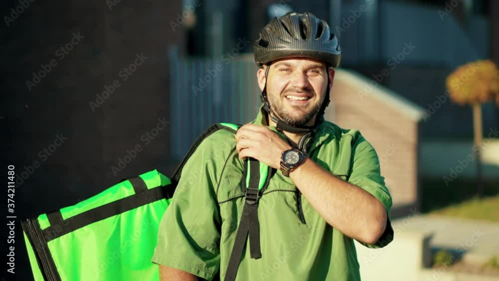 Portrait smiling attractive delivery man standing with bicycle backpack looking at camera in city job order courier shipping parcel package slow motion Portrait smiling attractive delivery man standing with bicycle backpack looking at camera in city job order courier shipping parcel package slow motion