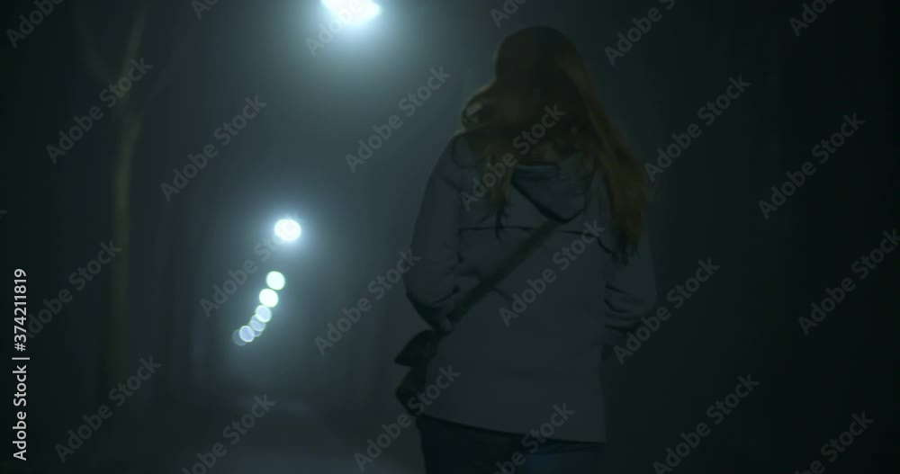 A woman walks alone on a dark alley at nighttime, The Netherlands. A woman walks alone on a dark alley at nighttime, The Netherlands.