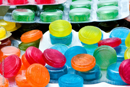 Medical lozenges for relief cough, sore throat and throat irritation . Cough and colds drop. Colorful cough pastille. Red, orange, yellow, and purple round candy or sweets ,Medical candies in blister 