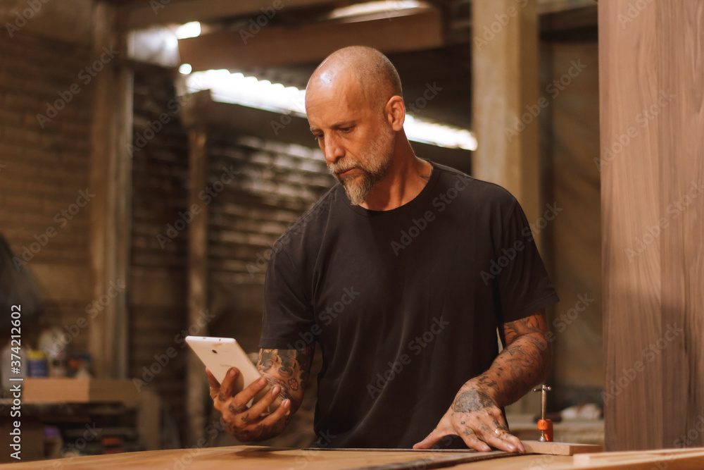 Carpintero mexicano trabajando en talle con tableta