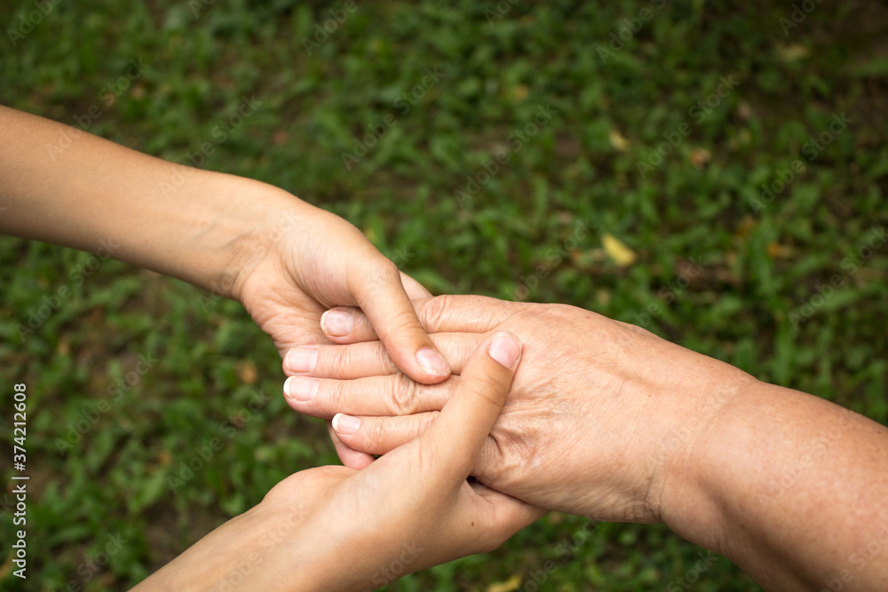 Hands of child gently hold the hands of grandmother against background of green grass. The concept of love and friendship between generations. National Day of Older Persons and Grandparents Day Hands of child gently hold the hands of grandmother against background of green grass. The concept of love and friendship between generations. National Day of Older Persons and Grandparents Day