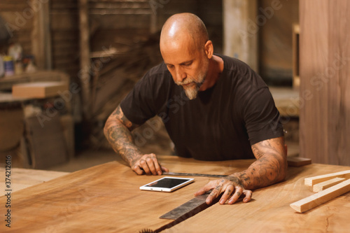 Carpintero mexicano trabajando en talle con tableta