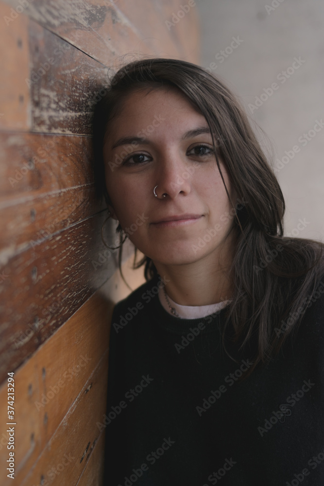 Joven mujer mirando hacia adelante apoyada en pared de madera Joven mujer mirando hacia adelante apoyada en pared de madera