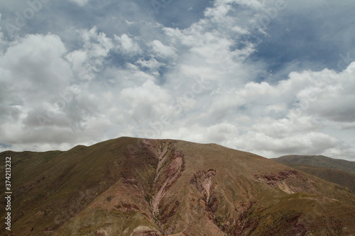 Andes mountain range. Aerial view of the brown mountain peak under a beautiful cloudy sky. 
