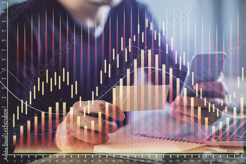 Double exposure of man s hands holding and using a phone and financial graph drawing. Analysis concept.