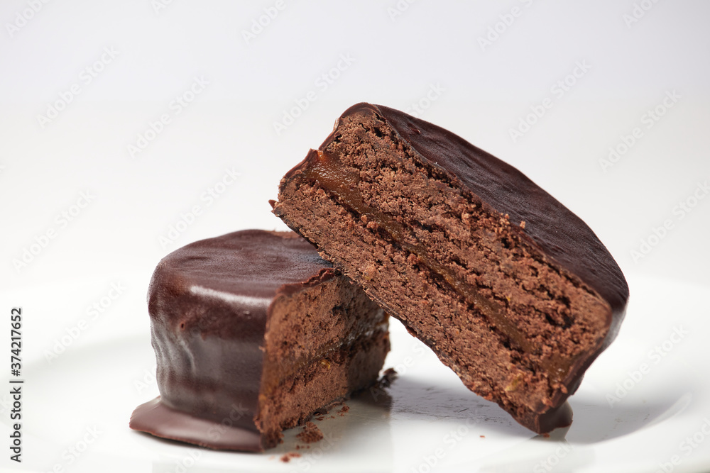 Typical Argentine Alfajor of dark chocolate cut in the middle where you can see the interior of chocolate and the filling of dulce de leche Typical Argentine Alfajor of dark chocolate cut in the middle where you can see the interior of chocolate and the filling of dulce de leche