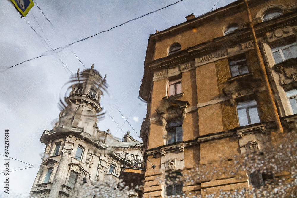 Old facade of a vintage building reflected in a muddy puddle