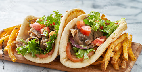 two greek gyros with fries, tomato and lettuce