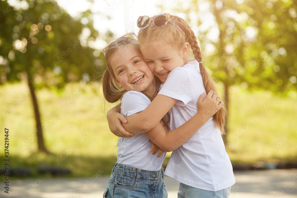 Two sisters pose for the camera outdoors in a Sunny Park. Selective focus Two sisters pose for the camera outdoors in a Sunny Park. Selective focus