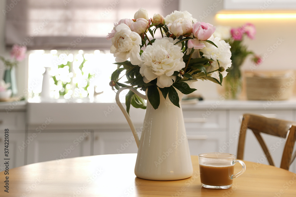 Beautiful peonies and cup of coffee on wooden table in kitchen. Space for text Beautiful peonies and cup of coffee on wooden table in kitchen. Space for text