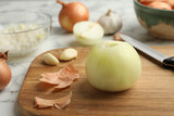 Peeled onion bulb and knife on wooden board