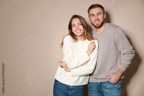 Lovely couple in warm sweaters on beige background. Space for text