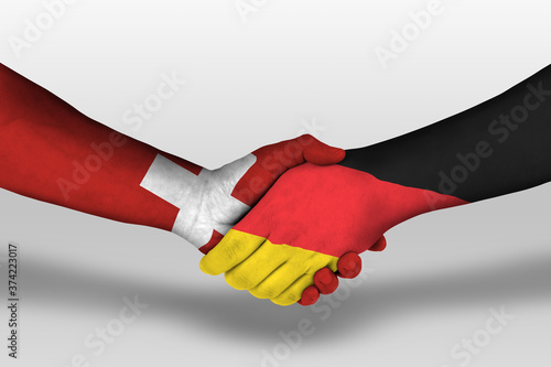 Handshake between germany and switzerland flags painted on hands, illustration with clipping path. photo