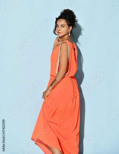 Studio portrait of beautiful attractive charming young brunette woman wearing greek inspired dress coral col