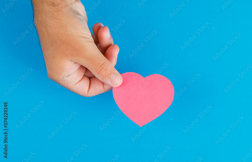 Fototapeta premium Relationship concept on blue background flat lay. hand holding paper cut heart.