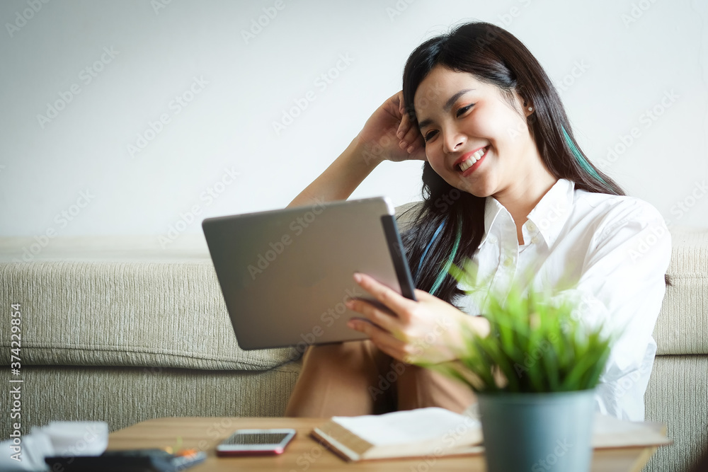 Woman hold with tablet at sit on sofa and use tablet happily at home. Woman hold with tablet at sit on sofa and use tablet happily at home.