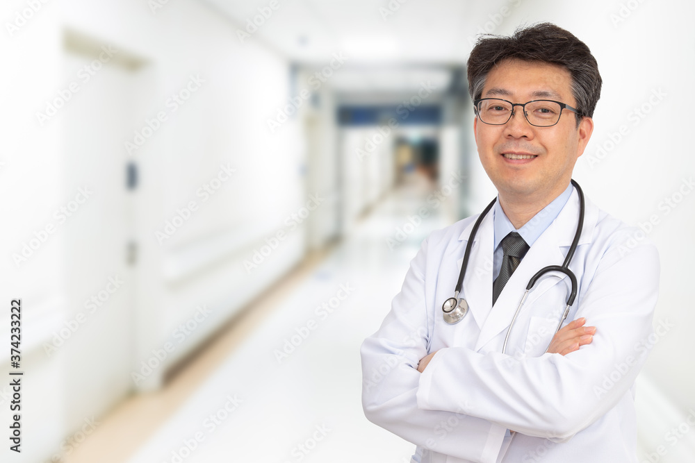 An Asian middle-aged male doctor smiling in the hospital corridor.