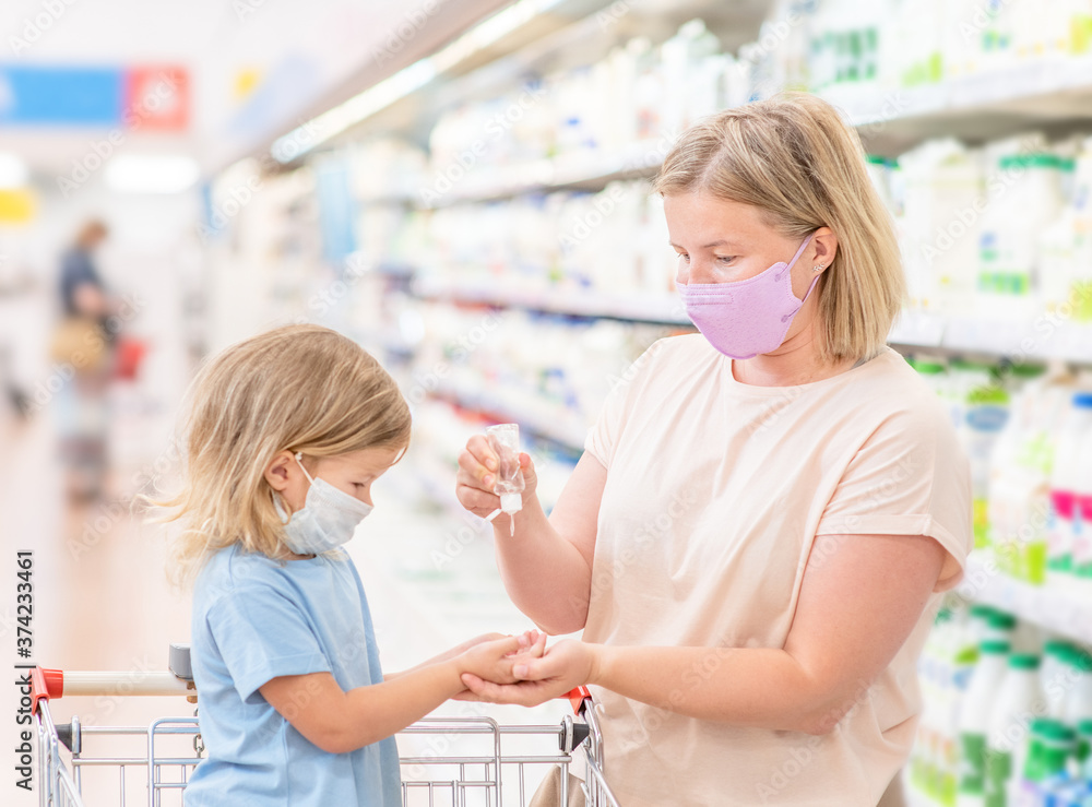 woman disinfects her daughter's hands in the store during coronavirus and flu outbreak woman disinfects her daughter's hands in the store during coronavirus and flu outbreak