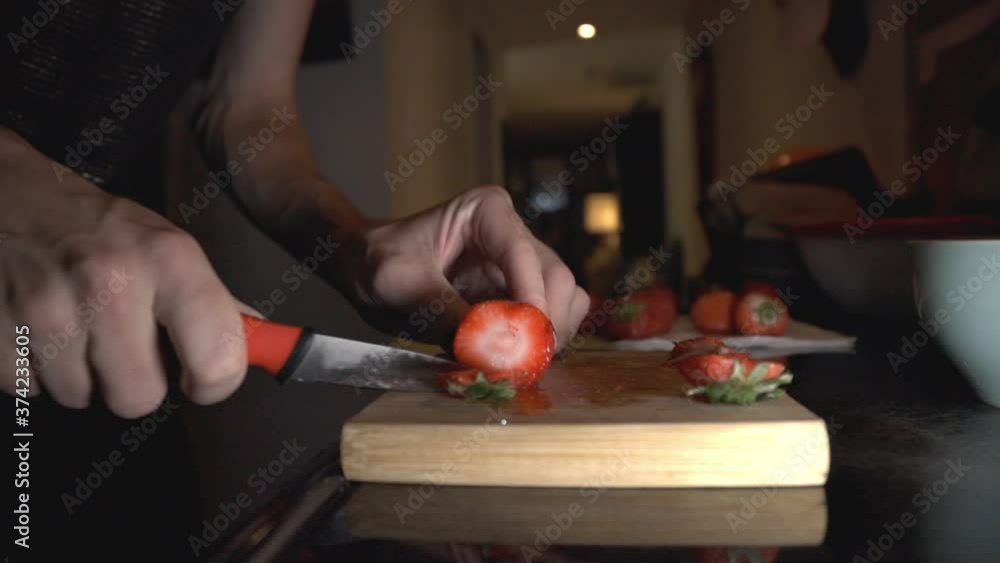 Slicing Strawberry Using Kitchen Knife On A Wooden Chopping Board. - close up shot Slicing Strawberry Using Kitchen Knife On A Wooden Chopping Board. - close up shot