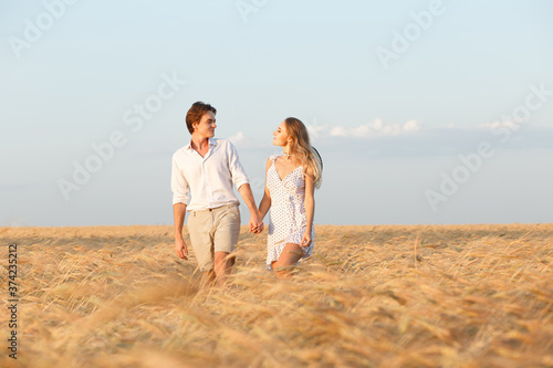 A couple in love in the summer walks in a cereal field