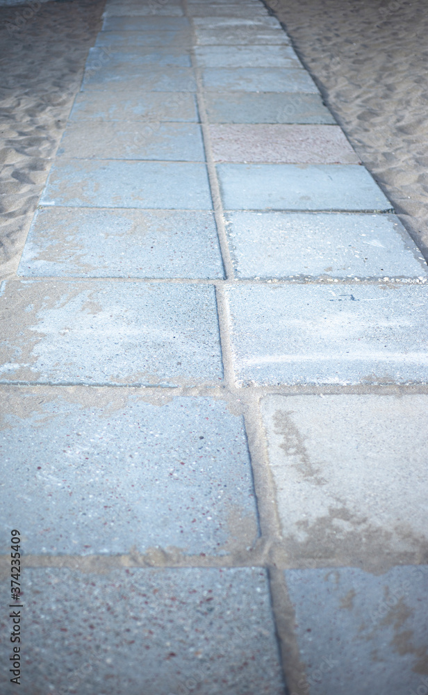  A path made of gray stone tiles with sand.