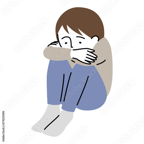 沈んだ表情で、うずくまって座る少年