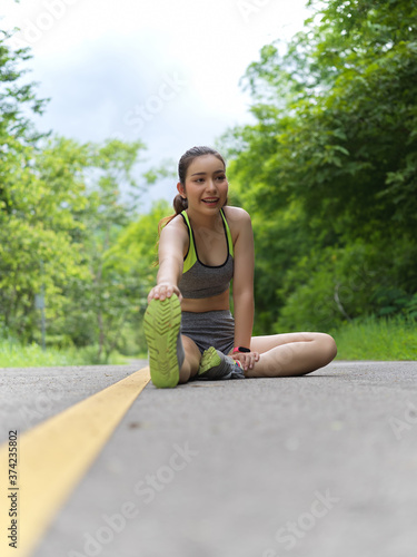 Portrait of female in sportswear stretching her leg to cool down